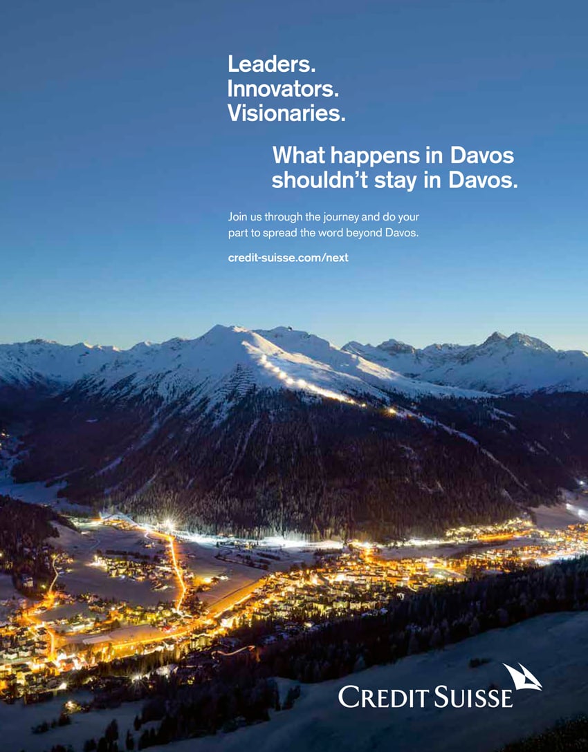 A tear sheet for Credit Suisse by the photography duo Scanderbeg Sauer. The tear sheet features a nightscape of a brightly lit town in front of snowy mountain. It looks like dusk.